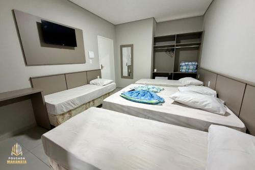 a room with three beds and a flat screen tv at Pousada Maranata in Aparecida