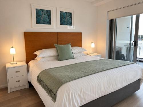 a bedroom with a large bed with two lamps and a window at Harbourfront Views at Allure 2 Bedroom Apartment in Townsville
