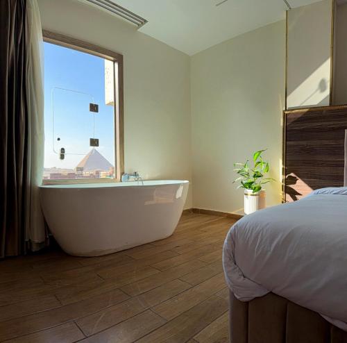 a bedroom with a tub and a bed and a window at Aura Grand pyramids view inn in Giza