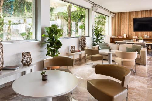 a waiting room with tables and chairs and windows at Meliá South Beach in Magaluf