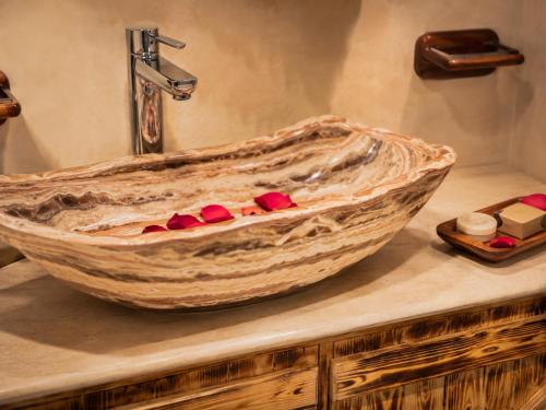 a bathroom sink with a large wooden bowl with red medicines at Hotel Paradise KMA in Bouznika