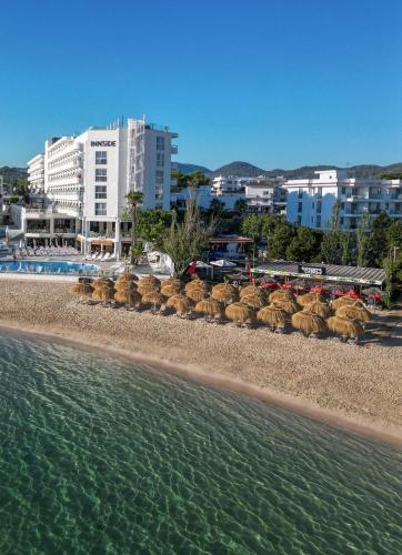 a beach with a group of straw chairs and the water at INNSiDE by Meliá Ibiza Beach in San Antonio Bay