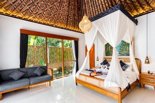 a bedroom with a canopy bed and a couch at Uma Harum Sari by Dhananjaya Hospitality in Penginyahan