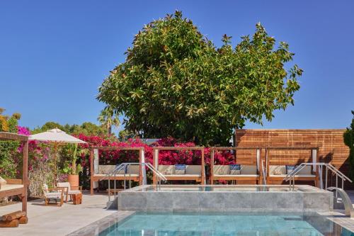 a pool with chairs and a tree in the background at ME by Meliá Ibiza - The Leading Hotels of the World in Santa Eularia des Riu