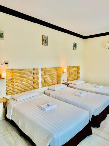 three beds in a room with white walls and windows at HOTEL MESRA ALOR SETAR in Alor Setar