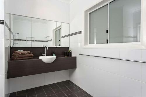 a white bathroom with a sink and a mirror at Harbour View Apartments in Ulladulla