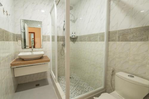 a bathroom with a shower and a toilet and a sink at Alona Garden Suites in Panglao Island