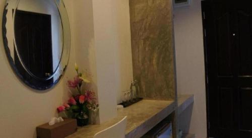 a bathroom with a mirror and flowers on a counter at Sabai @ Chumphae Hotel in Chum Phae
