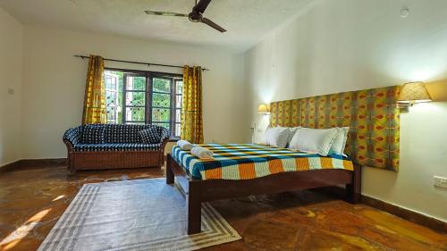a bedroom with a bed and a chair and a window at Janari Stays in Kilifi