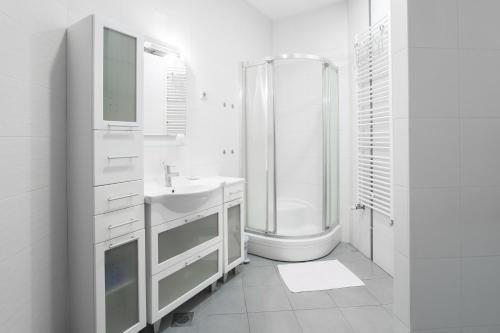 a white bathroom with a shower and a sink at Apartments Zagreb Point - Vinogradska in Zagreb