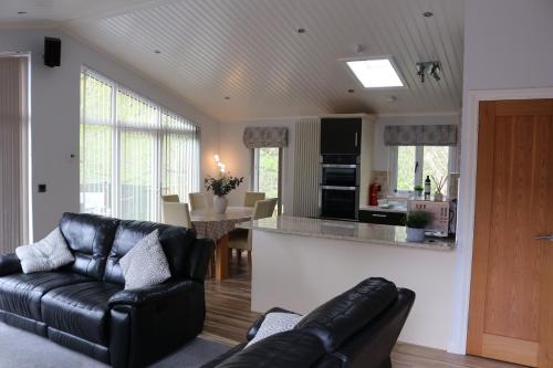 a living room with a black leather couch and a kitchen at High View Lodge in Windermere