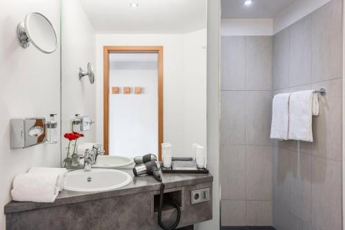 a bathroom with a sink and a mirror at Hotel Wolfsburg Centrum, Affiliated by Meliá in Wolfsburg
