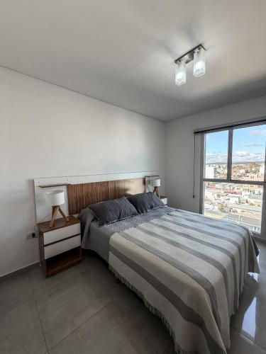 a bedroom with a large bed and a large window at Caleta VIEW - Alojamientos in Puerto Madryn