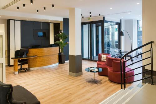 a lobby with a red chair and a desk at Hotel Paris Opéra, Affiliated by Meliá in Paris