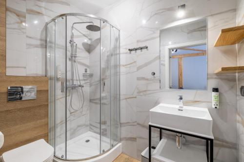 a white bathroom with a shower and a sink at Willa Folc in Kościelisko