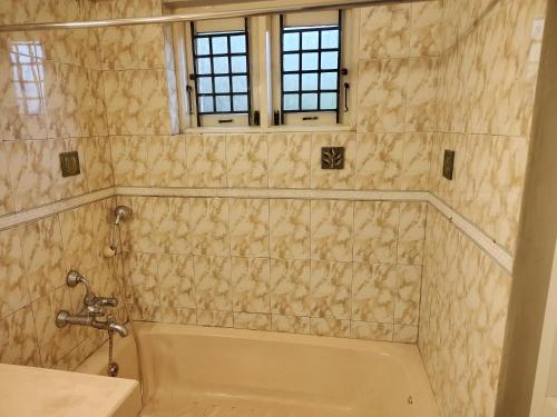 a bathroom with a tub and a sink and a window at Pear Mount Farm House in Kodaikānāl