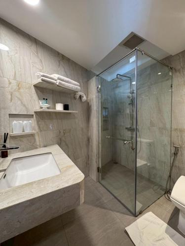 a bathroom with a shower and a sink and a tub at The Front Hotel and Apartments in Patong Beach