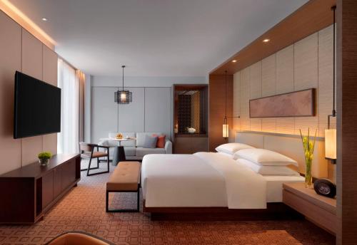 a bedroom with a large white bed and a living room at Zhenjiang Marriott Hotel in Zhenjiang
