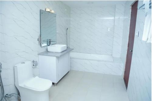 a white bathroom with a toilet and a sink at ila Comfort Harkapur in Maruwā Ghāt