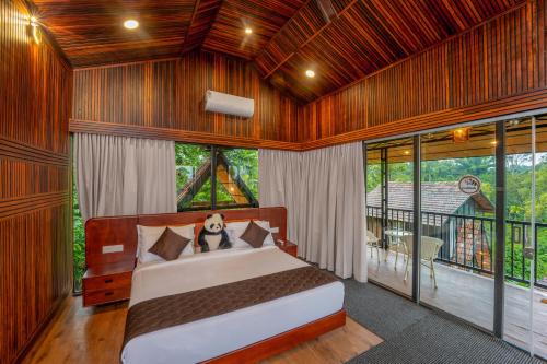 a bedroom with a bed and a balcony at Wood Panda Luxury Resort Wayanad in Meppādi