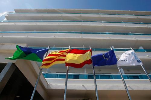 three flags on poles in front of a building at Hotel Natura Park in Comarruga