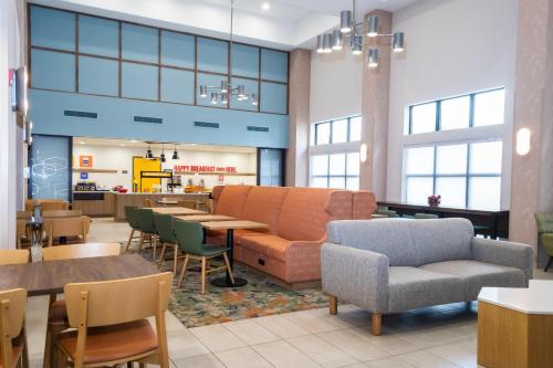 a restaurant with a couch and tables and chairs at Hampton Inn & Suites Addison in Addison