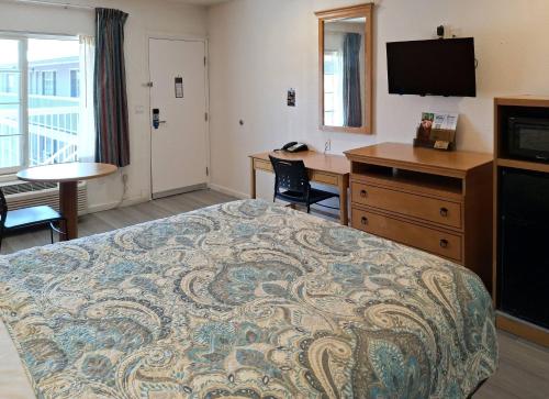 a hotel room with a bed and a desk and a television at Rodeway Inn Alameda-Oakland in Alameda