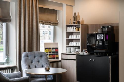 a room with a chair and a table and a tv at elaya hotel hannover city, Trademark by Wyndham in Hannover