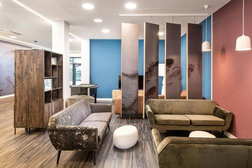 a lobby with a couch and chairs and a table at elaya hotel augsburg, Trademark by Wyndham in Augsburg