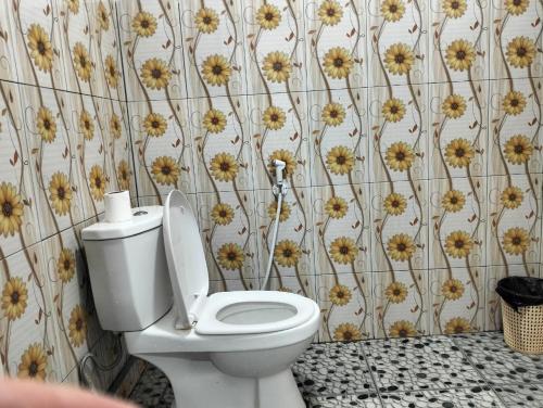 a bathroom with a toilet with flowers on the wall at Tengger Indah Seruni Bromo in Probolinggo