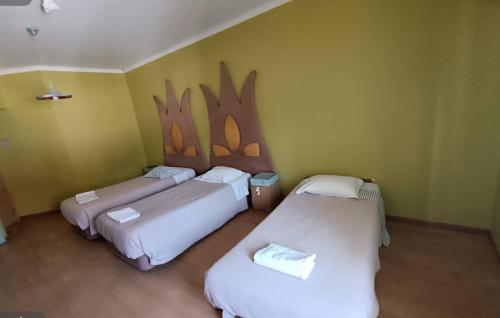 three beds in a room with a wall with drawings on it at Hotel Vitoria in Santarém
