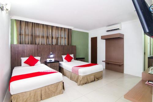 a bedroom with two beds with red pillows at Hotel O Crystal City Hotel in Kuantan