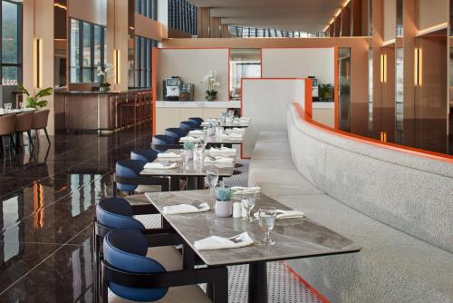 a row of tables in a restaurant with blue chairs at Harris Hotel & Conventions Sunshine Penang in Ayer Itam