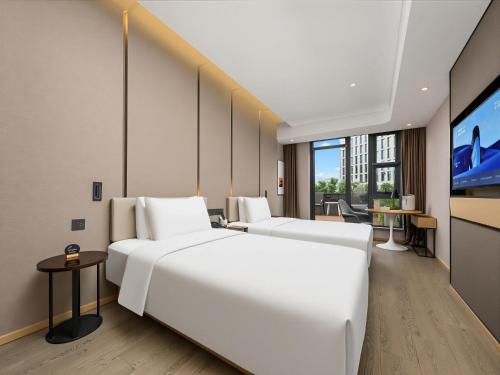 a hotel room with two beds and a flat screen tv at 北京三里屯天安门亚朵酒店 in Beijing