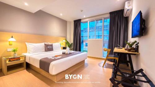a hotel room with a bed and a desk and a window at The Tapir Puchong by BYON Premium Suites & Hotels in Puchong