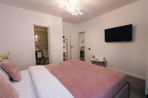 a bedroom with a bed and a flat screen tv at RR House Apartments in Râşnov