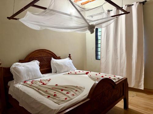 a bedroom with a bed with red roses on it at Tropinest bungalows & hostel in Nungwi