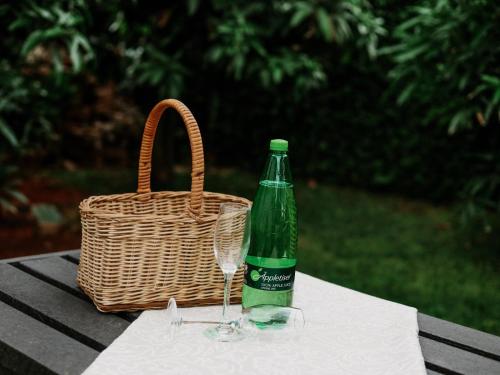 a bottle and a wine glass on a table with a basket at El Palmar Guesthouse in Groblersdal