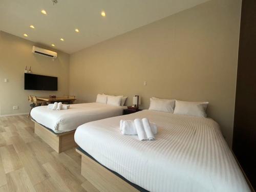 a bedroom with two beds with white towels on them at OKINAWA GREEN LODGE in Okinawa City