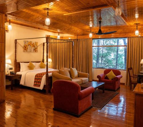a hotel room with a bed and two chairs at Chillaru Spa & Resort in Kasauli