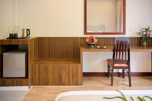a room with a desk with a chair and a mirror at THE RIVERFRONT CENTRAL Hotel in Siem Reap