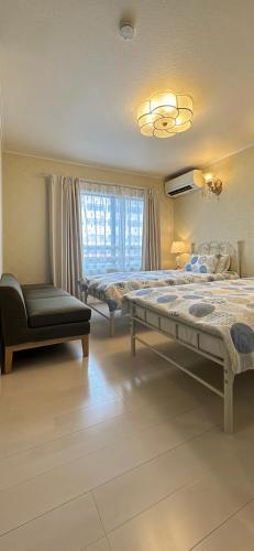 a bedroom with two beds and a chair and a window at guesthouse嵐 in Osaka
