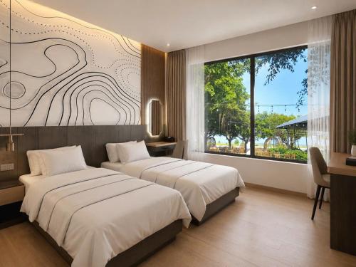 a bedroom with two beds and a large window at Dragon Hotel in Rạch Giá