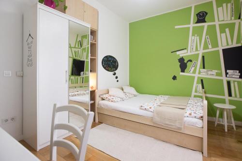 a small room with a bed and a green wall at Apartment Witty Please in Zagreb