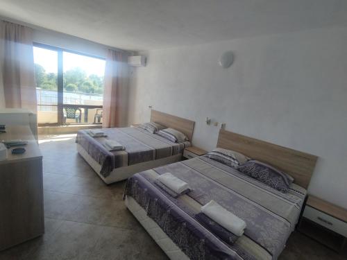 two beds in a room with a large window at Tangra Guest House in Arapya