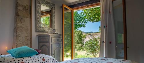a bedroom with a bed and a large window at Hameau d'hôtes La Roseraie-Drôme in Condorcet