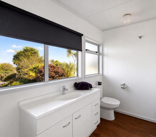 a white bathroom with a sink and a window at Taupo Debretts Spa Resort in Taupo
