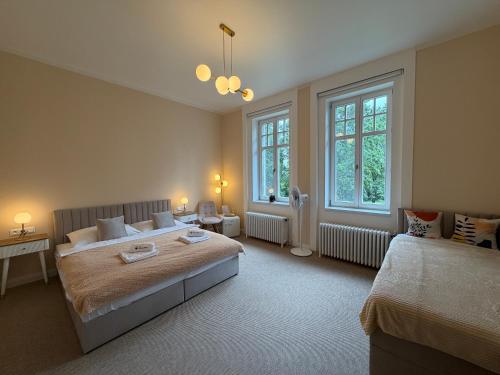 a bedroom with two beds and two windows at Vila Na Landeku in Ostrava