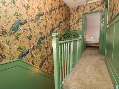 a hallway with a staircase with peacock wallpaper at 8 Manor Villas in Totland