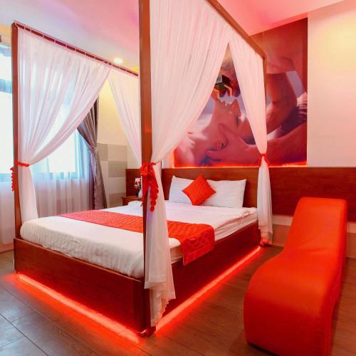 a bedroom with two beds and a red chair at Đào Hoa Mộng Couple Hotel - Central & City View in Quy Nhon